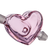 A close-up of the MJ Arsenal Cupid's Bow(l) Valentine's Day Glass Pipe, a glossy pink heart-shaped borosilicate pipe with two angled openings and a central hole, displayed against a white background.