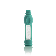 The Grav 16mm Octo-Taster w/Silicone Skin is a teal portable pipe with a clear midsection displaying "GRAV," a rounded mouthpiece, and a compact, sturdy design, shown standing upright against a white background.