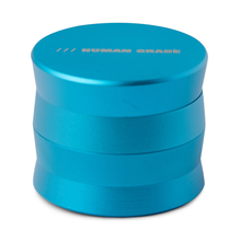 The Human Grade Grinder 3A (2" 4-Piece) is a metallic blue aluminum grinder with a screw-on lid labeled HUMAN GRADE. It features a sleek, modern, slightly curved design and measures 2 inches across for convenient use.