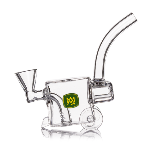 The MJ Arsenal Woodchipper Blunt Bubbler is a clear glass water pipe shaped like a wheeled cart, featuring a yellow and green logo, curved mouthpiece, angled bowl, and spill-resistant filtration for smoother hits.