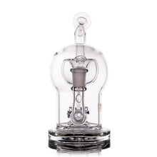 The MJ Arsenal The Plasma Core Rig is a clear borosilicate glass water pipe featuring a rounded dome, central downstem, and circular base, standing upright on a reflective surface—crafted in the signature Plasma Core style.