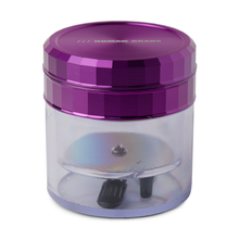 The Human Grade Storage Grinder 1A (2.5") is a small, cylindrical 4-piece grinder with a shiny purple lid featuring subtle text and a clear body that reveals the aluminum grinder and two small black knobs inside.