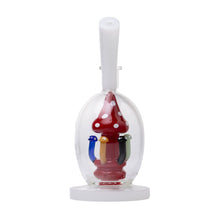 A clear dome covers a red, white-spotted mushroom inside the Human Grade Mushroom Globe Glass Rig, surrounded by five colorful figures on a white base with an upright handle—crafted from borosilicate glass.