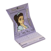 The Blazy Susan Purple Rolling Papers deluxe kit features a purple booklet with a cartoon woman, blue headband, and blouse, opened to show king size slim patterned rolling papers and folding instructions.